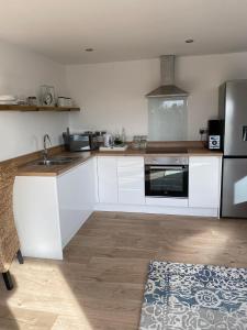 a kitchen with white cabinets and a stainless steel refrigerator at Spacious Studio Cabin with Sea/ Downs views Sole Use of HotTub in Seaford in Seaford