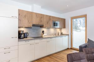 a white kitchen with white cabinets and a window at Apart Auszeit in Niederthai