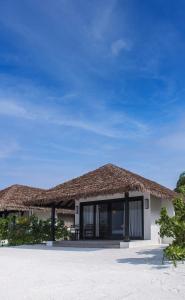 ein Resortgebäude mit einem Strohdach am Strand in der Unterkunft NOOE Maldives Kunaavashi in Fulidhoo