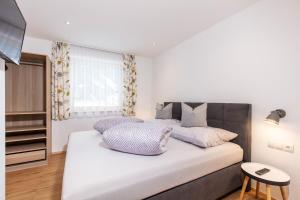 a bedroom with a large white bed with purple pillows at Apart Auszeit in Niederthai