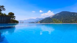 a large pool of blue water with mountains in the background at Shola Crown Resort - Munnar in Chinnakanal