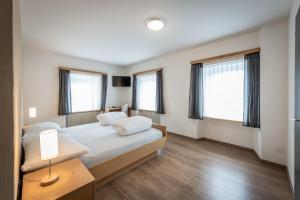 a bedroom with a bed and two windows at Hotel Greina in Rabius