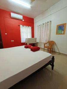 a bedroom with a bed and a red wall at RiTAS in Varkala