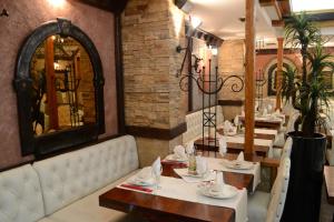 comedor con mesas blancas y espejo en Hotel Tomce Sofka, en Skopje