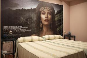 a large painting of a woman on a wall next to a bed at Hostal/Restaurante Fuentevieja in Illana