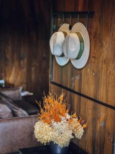 a pair of hats hanging on a wall with a vase of flowers at LUTS Chalés in Gonçalves