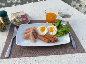 a plate of food with eggs and sausage and a glass of orange juice at Phala Shore Resort 