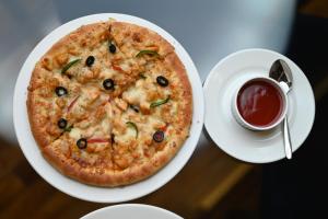 a pizza on a plate next to a cup of sauce at Royal Regency Hotel in Islamabad +48 photos
