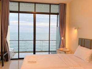 a bedroom with a large window with a view of the ocean at Phala Shore Resort 