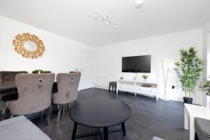 ein Wohnzimmer mit einem Tisch und Stühlen sowie einem TV in der Unterkunft Stylish House with Garden and Parking in Glasgow