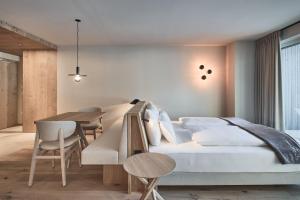 1 dormitorio con 1 cama, mesa y sillas en AMA Stay, en San Vigilio Di Marebbe