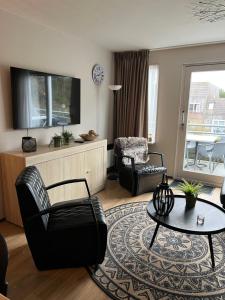 uma sala de estar com um sofá, uma cadeira e uma mesa em Appartement Ut & Thus, Resort Amelander Kaap em Hollum