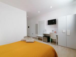 Habitación blanca con cama amarilla y escritorio. en Charme Suite B&B Experience en Santa Teresa Gallura