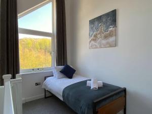 a bedroom with a bed and a large window at Modern Duplex Apartment with Woodland Views in Swansea