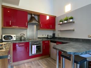 uma cozinha com armários vermelhos e uma bancada em Modern Duplex Apartment with Woodland Views em Swansea