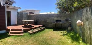 a backyard with a wooden table and a fence at David Bongers Still Bay Holiday Home in Stilbaai