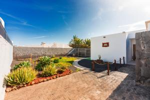 einen Backsteinsteg neben einem weißen Gebäude mit Pflanzen in der Unterkunft CASA DANEO in Playa Blanca