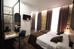 una camera d'albergo con letto, scrivania e letto. di Hotel BH San Francisco Alicante ad Alicante
