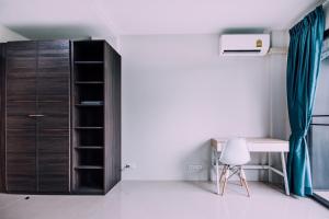 a bedroom with a desk and a cabinet and a chair at The Living Hotel SamutPrakan in Bang Bo