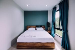 Un dormitorio con una cama con paredes azules y una ventana en The Living Hotel SamutPrakan en Bang Bo