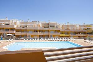 a large swimming pool with chairs and a building at Apartamento Duja in Cabanas de Tavira