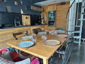 a wooden table with plates and wine glasses on it at Le Gambrinus - Loft Rochelais in La Rochelle +7 photos
