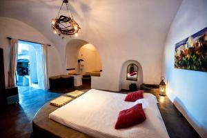 a bedroom with a large white bed with red pillows at Super Luxury Santorini Villa Mansion Kyani Private Pool 3 BDR Megalochori in Megalochori