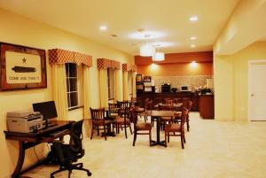 a dining room with tables and chairs and a kitchen at Westwood Inn & Suites in Gonzales