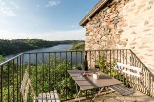 a table on a balcony with a view of a river at Gîtes Les Pittoresques in Saint-Jean-Saint-Maurice-sur-Loire