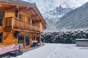 a log cabin with snow covered mountains in the background at Les Drus - Luxury Chalet for 8 in Chamonix-Mont-Blanc