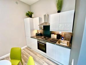 una pequeña cocina con armarios blancos y sillas verdes en Sunridge Cubes (Cube 1), en Plymouth