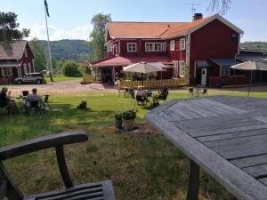 a group of people sitting in a yard with a red house at Sjugare Gård Glamping in Leksand