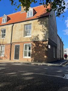 a brick building with a red roof on a street at Willow House - 2bed Townhouse with free parking!! by Shortstays4U in Kings Lynn