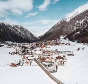 una piccola cittadina nella neve con le montagne di Familienhotel Huber a Valles