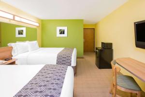 a hotel room with two beds and a flat screen tv at Microtel Inn & Suites by Wyndham Delphos in Delphos