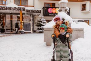 twee kinderen staan in de sneeuw bij Familienhotel Huber in Valles