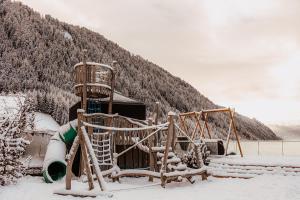 a playground in the snow in front of a house at Familienhotel Huber in Valles