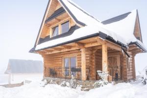 a log cabin with a snow covered roof at Góralskie Domki Zakopane Gubałówka in Zakopane
