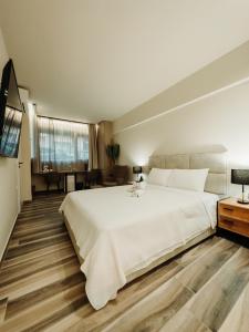 um quarto com uma grande cama branca e pisos em madeira em BLACKHAUS FAMILY AND FRIENDS DELUXE APARTMENT em Tessalônica