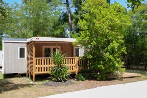 une petite cabane avec une véranda et un arbre dans l'établissement CAMPING LES OURMES, à Hourtin