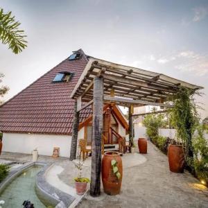 een huis met een houten dak en een zwembad bij susil house villa in Vellore