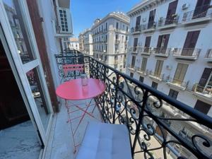 einen kleinen rosa Tisch auf einem Balkon mit Gebäuden in der Unterkunft Napoli Da Vivere Suites Giudecca in Neapel