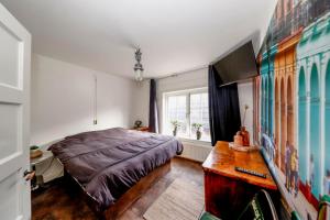 een slaapkamer met een bed, een bureau en een televisie bij city-apartment een hele verdieping voor jezelf midden in het centrum in Apeldoorn