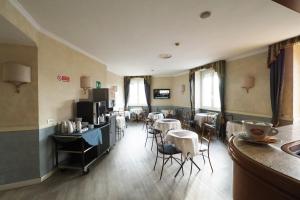 Hotel Laura في روما: غرفة معيشة مع طاولات وكراسي ومطبخ