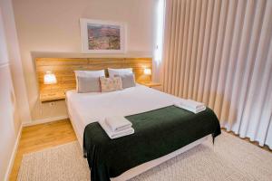 una camera da letto con un grande letto bianco con due asciugamani di Casa das Letras - Turismo rural a Ponte da Barca