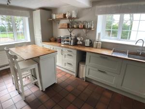 a kitchen with white cabinets and a wooden counter top at Large Country Farmhouse with Garden and Stream in Doagh