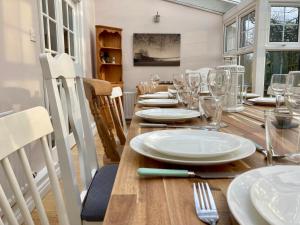 una sala da pranzo con tavolo in legno, piatti e bicchieri di Large Country Farmhouse with Garden and Stream a Doagh