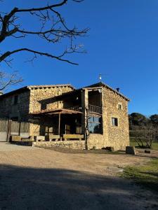 um velho edifício de pedra com uma árvore em frente em Mas Sabaters - L'Era de Sabaters em Tavernoles