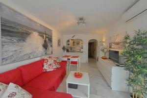 sala de estar con sofá rojo y cocina en Tranquilo , soleado cerca de la playa, en Torremolinos