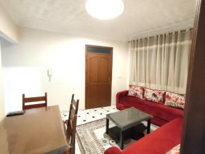 uma sala de estar com um sofá vermelho e uma mesa em City Centre Apartment - New Deco em Tânger